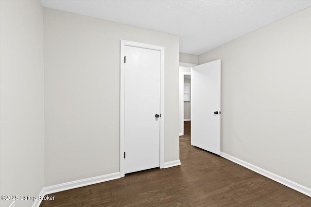 unfurnished room with dark hardwood / wood-style floors and a textured ceiling