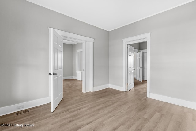 unfurnished bedroom featuring crown molding and light wood-type flooring