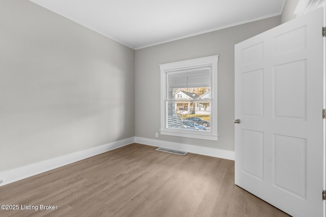 spare room featuring crown molding and light hardwood / wood-style floors