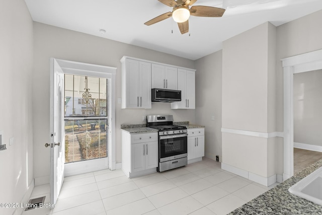 kitchen featuring light stone countertops, appliances with stainless steel finishes, light tile patterned floors, and white cabinets