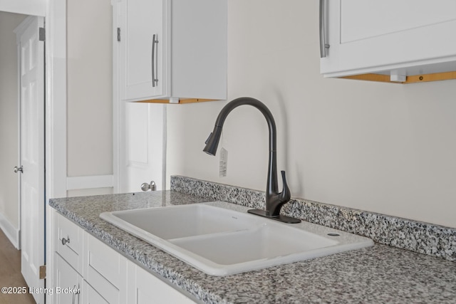 details featuring white cabinetry, sink, and light stone counters