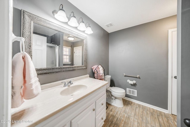 bathroom featuring vanity, hardwood / wood-style flooring, toilet, and walk in shower