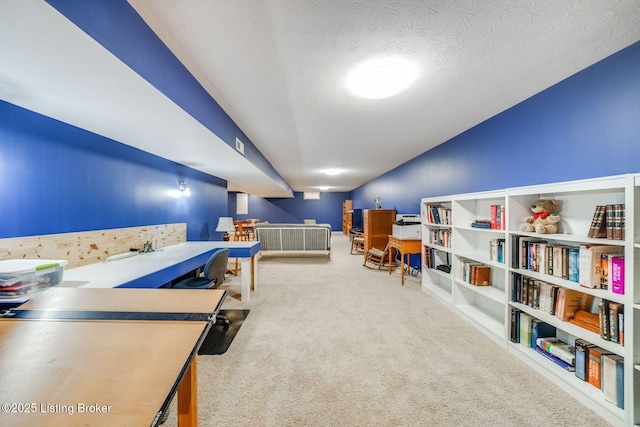 recreation room featuring vaulted ceiling, a textured ceiling, and carpet