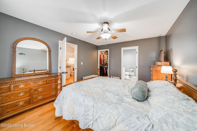 bedroom featuring light wood-type flooring, a spacious closet, ceiling fan, ensuite bath, and a closet