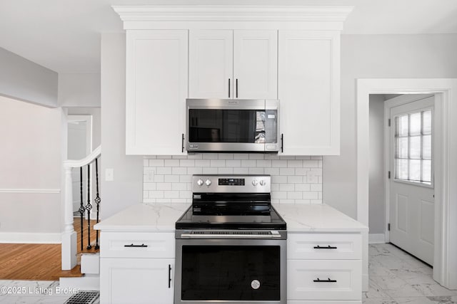 kitchen featuring white cabinetry, light stone countertops, backsplash, and stainless steel appliances