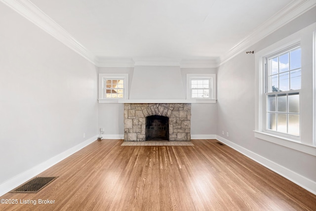 unfurnished living room with ornamental molding, a stone fireplace, and hardwood / wood-style floors