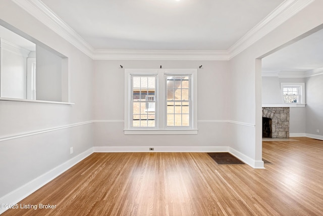 unfurnished room with hardwood / wood-style floors, crown molding, plenty of natural light, and a fireplace