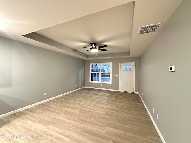 interior space featuring a tray ceiling, light hardwood / wood-style flooring, and ceiling fan