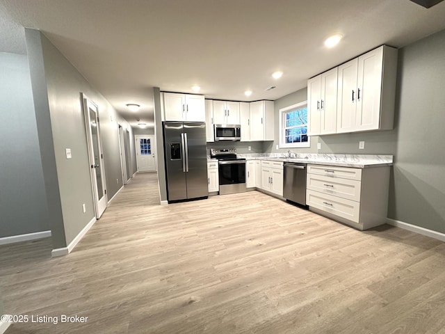 kitchen featuring white cabinetry, sink, light hardwood / wood-style flooring, and appliances with stainless steel finishes