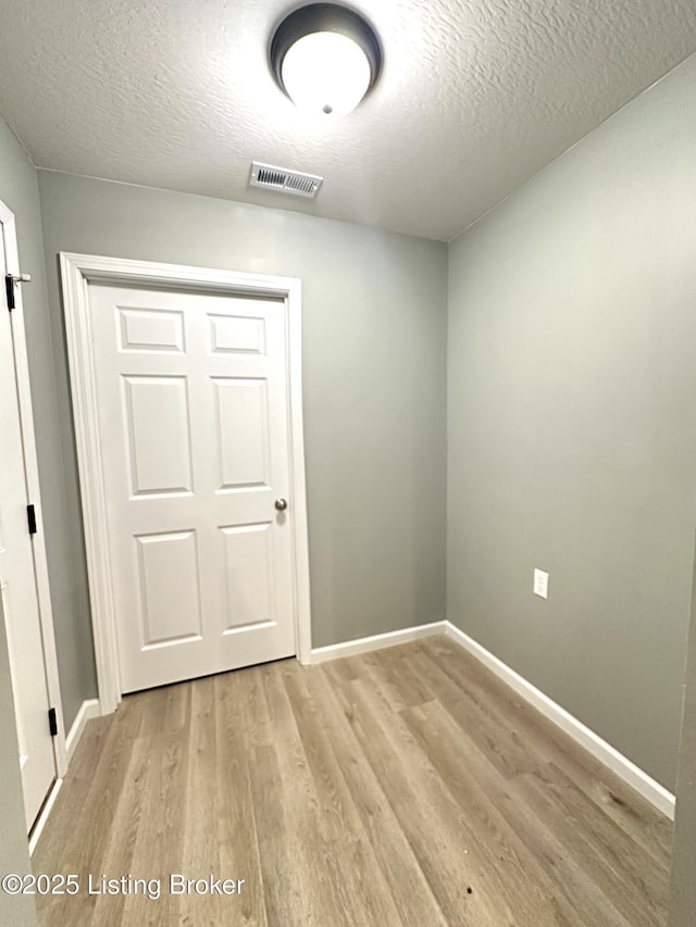 spare room with light hardwood / wood-style floors and a textured ceiling