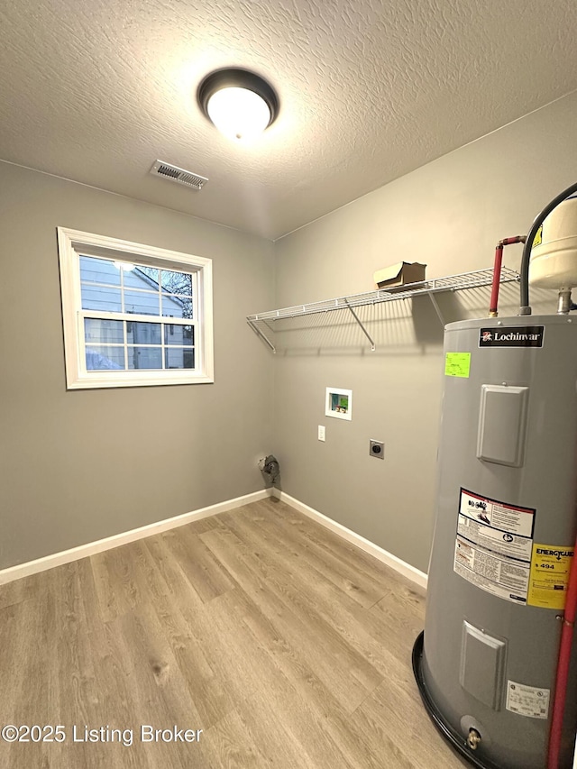 washroom with hookup for a washing machine, electric dryer hookup, electric water heater, a textured ceiling, and light hardwood / wood-style flooring