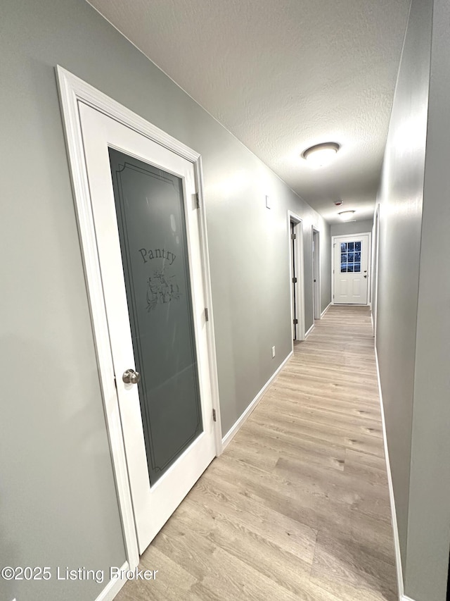 corridor with light hardwood / wood-style flooring and a textured ceiling