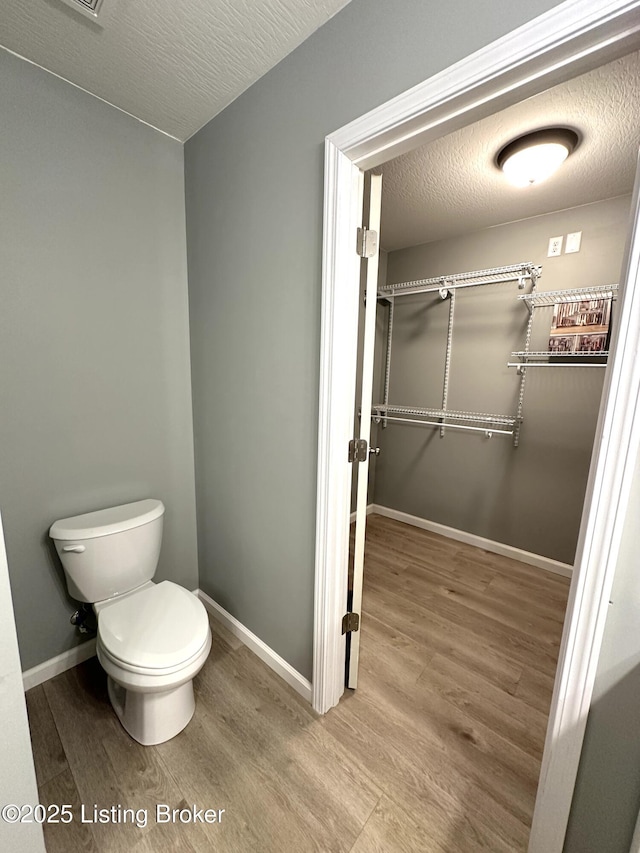 bathroom with hardwood / wood-style flooring, toilet, and a textured ceiling