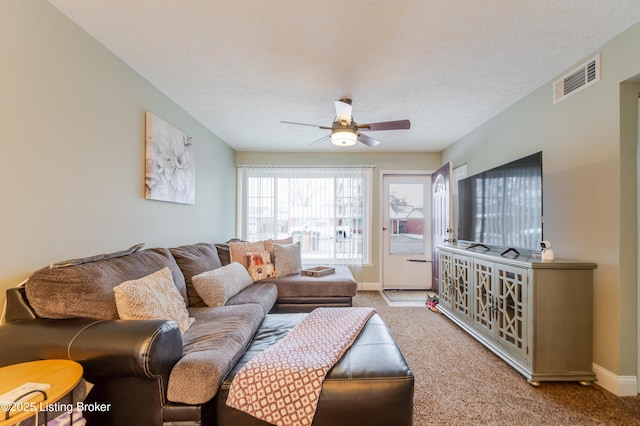 carpeted living room with ceiling fan and a textured ceiling