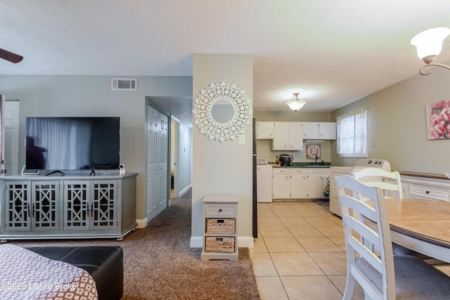 kitchen featuring light tile patterned flooring, washer / dryer, sink, white cabinets, and stove