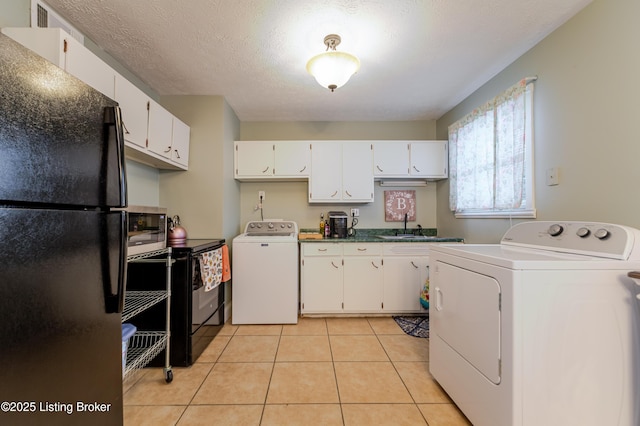 interior space with washer / clothes dryer, white cabinetry, black refrigerator, and light tile patterned flooring