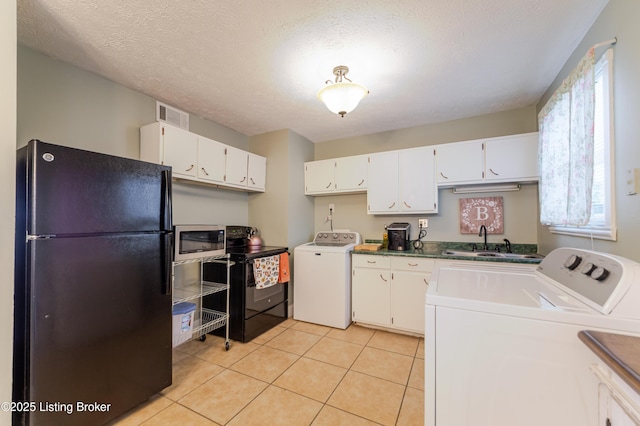 kitchen featuring sink, light tile patterned floors, black appliances, and white cabinets