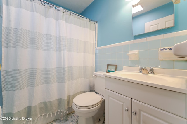 bathroom featuring vanity, toilet, curtained shower, and tile walls