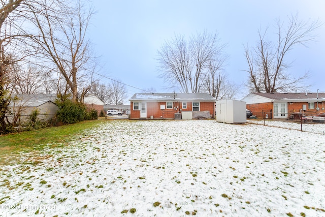 snow covered back of property featuring a shed