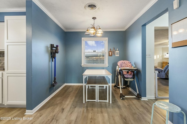 interior space featuring a notable chandelier, light hardwood / wood-style flooring, ornamental molding, and a textured ceiling