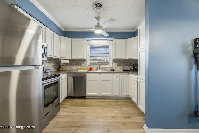 kitchen with white cabinetry, sink, crown molding, and stainless steel appliances