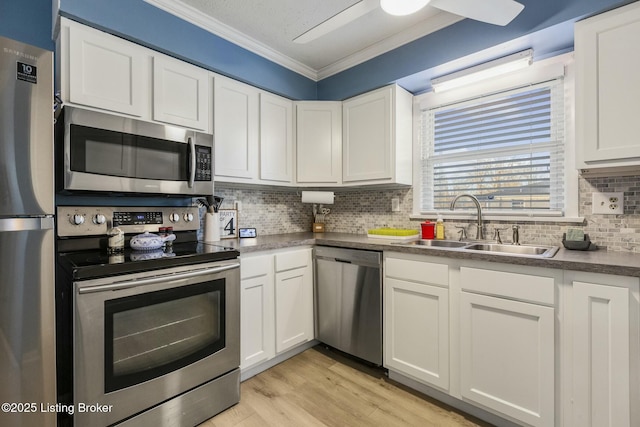 kitchen with crown molding, stainless steel appliances, sink, and white cabinets