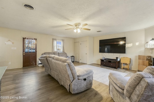 living room with hardwood / wood-style flooring, ceiling fan, and a textured ceiling