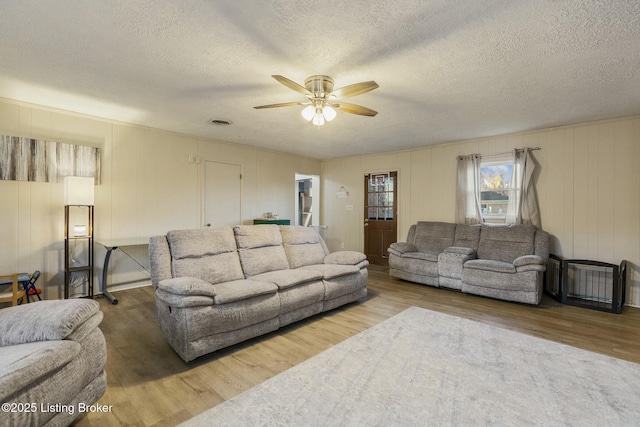 living room featuring hardwood / wood-style floors, a textured ceiling, and ceiling fan