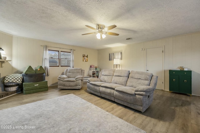 living room with wood-type flooring, a textured ceiling, and ceiling fan