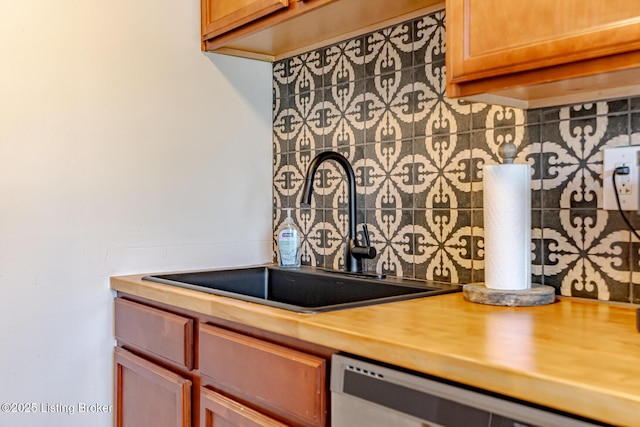 kitchen featuring wood counters, stainless steel dishwasher, and sink