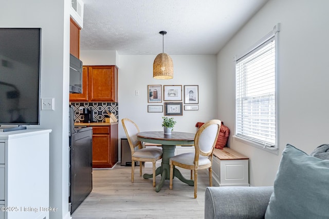 dining space featuring a textured ceiling and light wood-type flooring