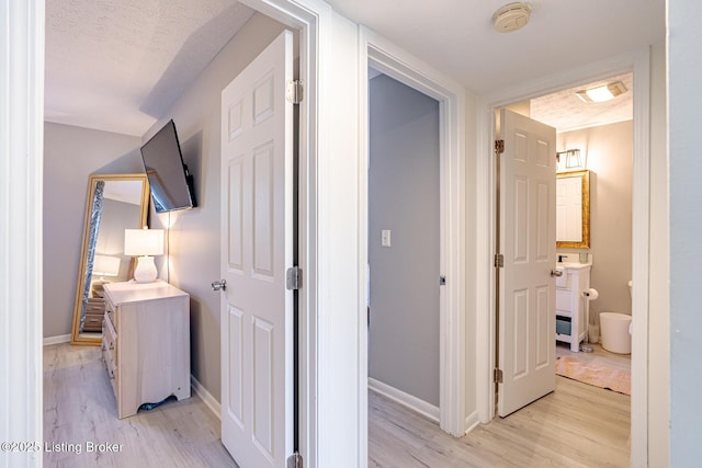 hallway featuring a textured ceiling and light wood-type flooring