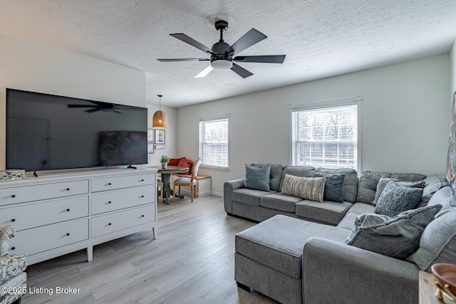 living room featuring ceiling fan, light hardwood / wood-style floors, and a textured ceiling