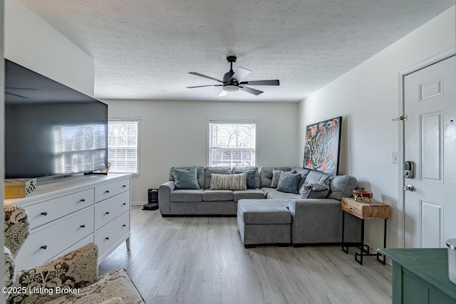 living room with ceiling fan, a textured ceiling, and light hardwood / wood-style flooring