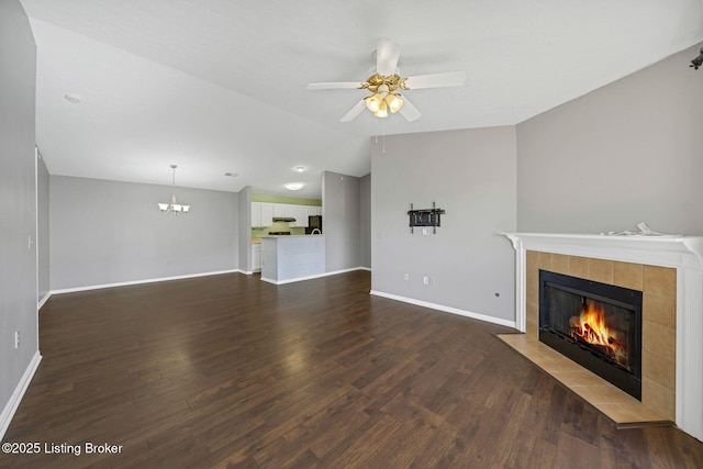 unfurnished living room with dark hardwood / wood-style flooring, ceiling fan with notable chandelier, vaulted ceiling, and a tile fireplace