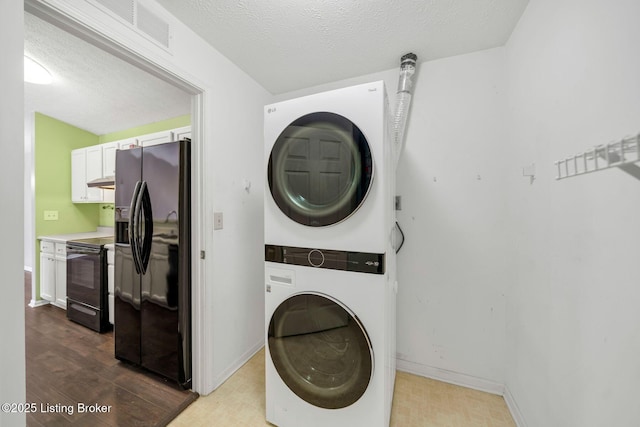 laundry area with stacked washer and clothes dryer, hardwood / wood-style floors, and a textured ceiling