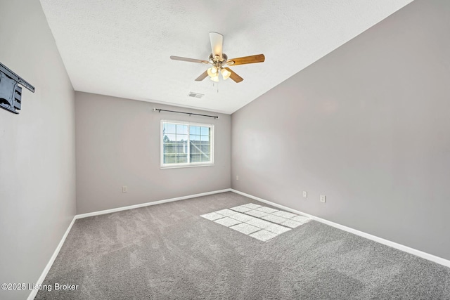 carpeted spare room featuring ceiling fan, lofted ceiling, and a textured ceiling