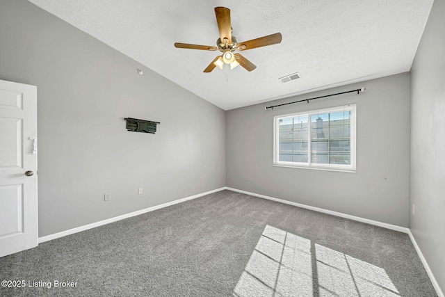 empty room featuring vaulted ceiling, carpet, ceiling fan, and a textured ceiling