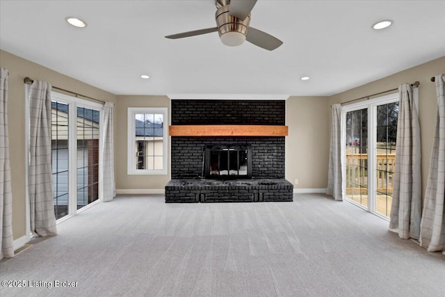 unfurnished living room with light carpet, a brick fireplace, and ceiling fan