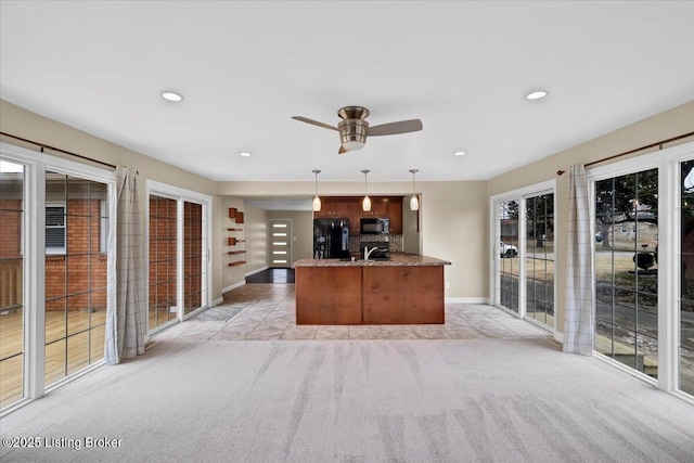 kitchen with stone counters, hanging light fixtures, black appliances, light carpet, and kitchen peninsula