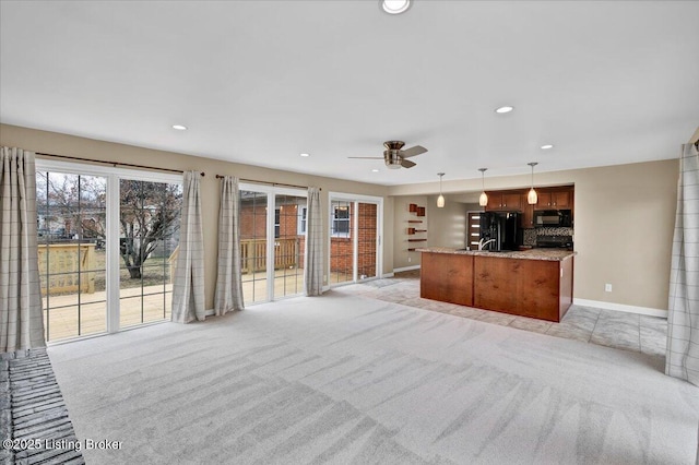 unfurnished living room featuring light carpet and ceiling fan