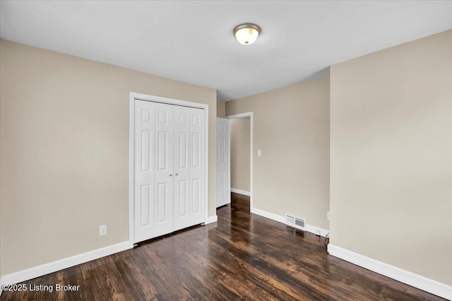 unfurnished bedroom with dark hardwood / wood-style floors and a closet