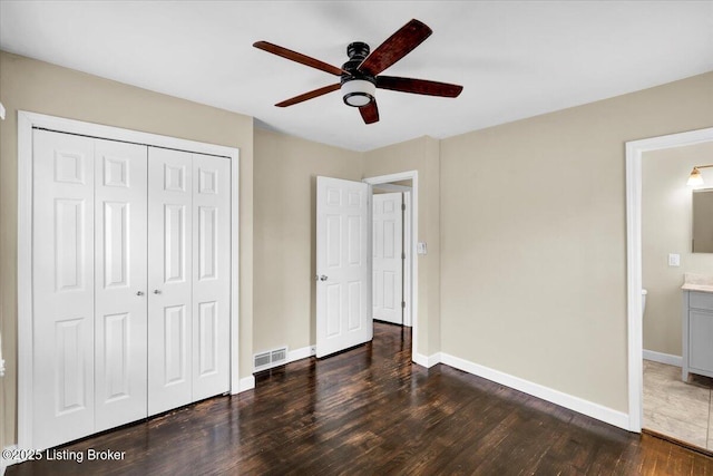 unfurnished bedroom featuring dark wood-type flooring, ceiling fan, connected bathroom, and a closet