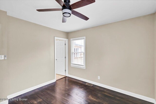 spare room with dark wood-type flooring and ceiling fan