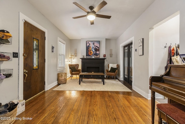 living area featuring ceiling fan, wood-type flooring, and a fireplace