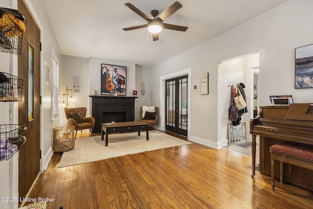 sitting room with french doors, ceiling fan, a fireplace, and light hardwood / wood-style floors