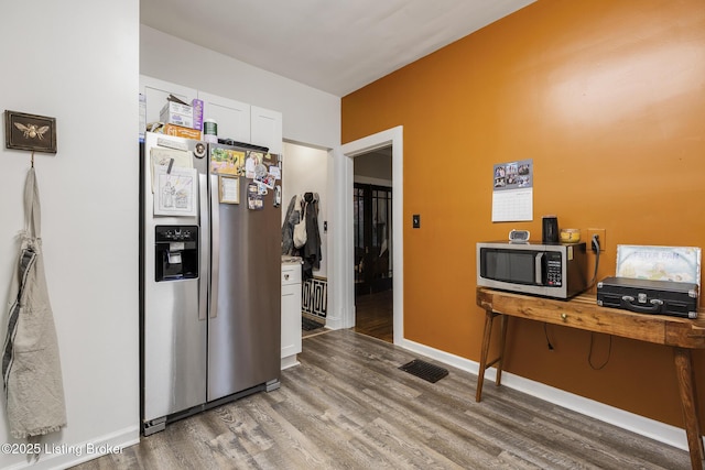 kitchen with wood-type flooring, stainless steel appliances, and white cabinets