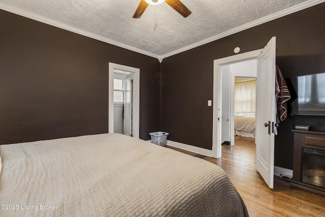 bedroom featuring hardwood / wood-style flooring, crown molding, ceiling fan, and a textured ceiling