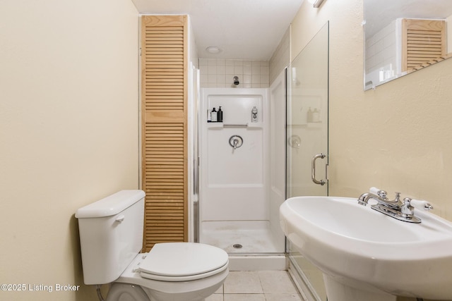 bathroom featuring walk in shower, tile patterned floors, toilet, and sink