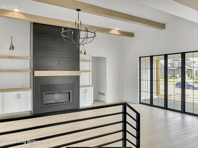 unfurnished living room featuring an inviting chandelier, beam ceiling, light hardwood / wood-style flooring, and a large fireplace